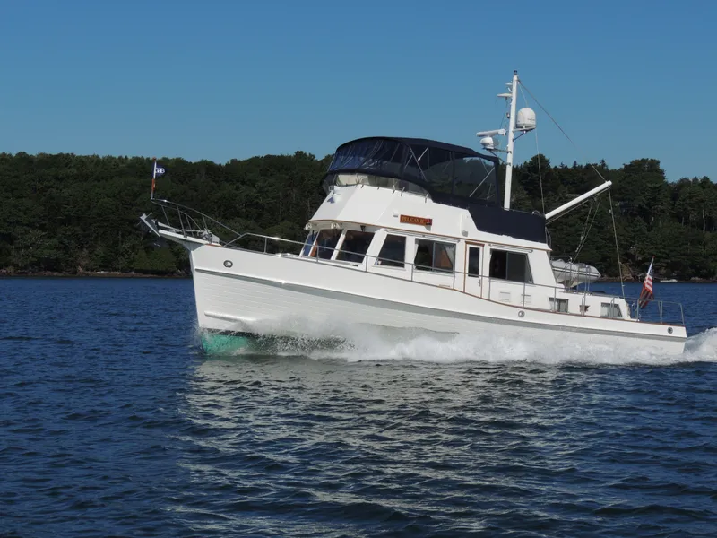 Slide: The Image of Grand Banks 42 Classic 2002 yacht cruising on a calm lake with forested shoreline. - 12