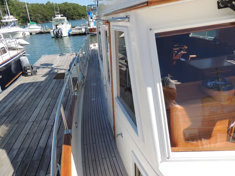 Slide: The Image of 2002 Grand Banks 42 Classic yacht docked at marina, showcasing sleek design and wooden accents. - 23