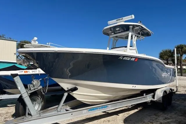 The Image of 2018 Tidewater 252 CC Adventure boat on trailer, blue hull, parked outdoors. - 1
