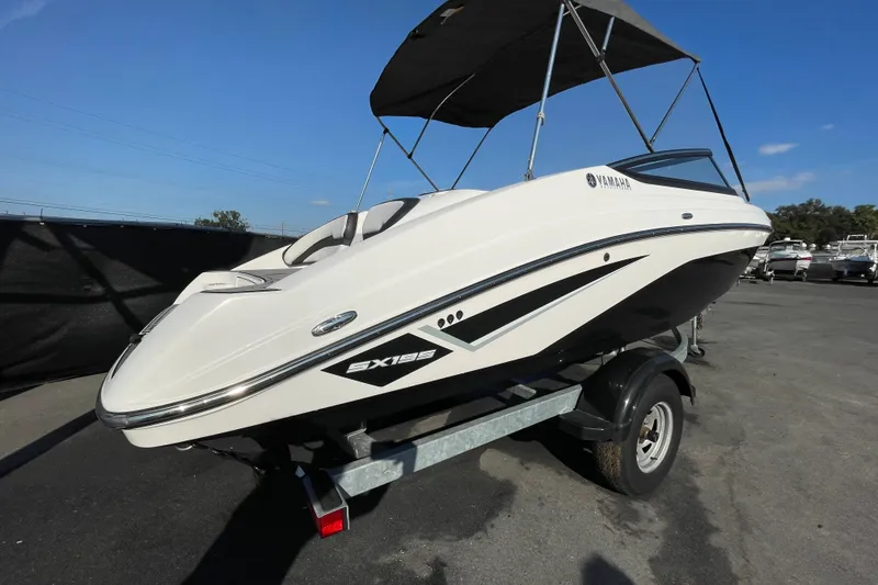Slide: The Image of 2019 Yamaha Boats SX195 on trailer, under cloudy sky, with bimini top. - 2