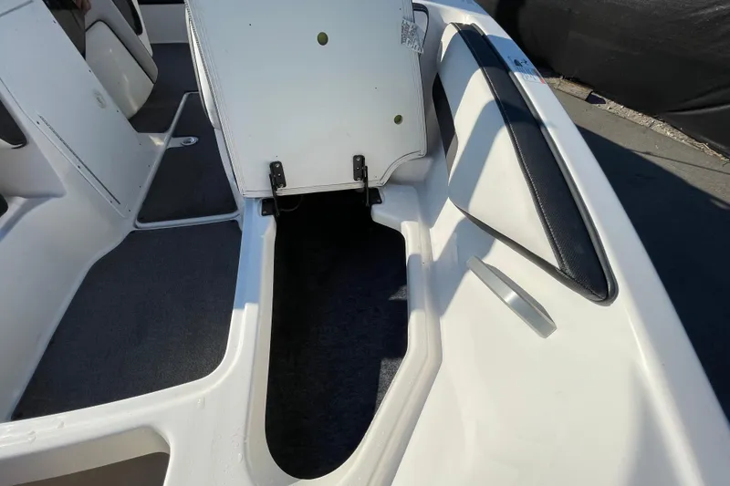 Slide: The Image of 2019 Yamaha Boats SX195 storage compartment with black mat and carpeted flooring. - 35