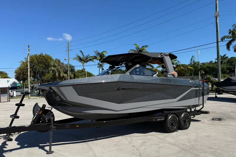 The Image of 2026 Nautique Super Air Nautique G25 Coastal Edition boat on trailer, sunny day. - 0