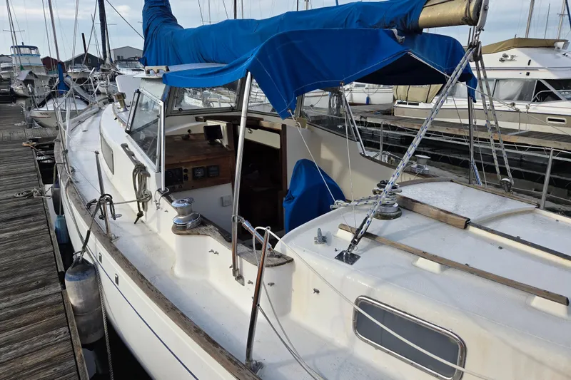 Slide: The Image of 1974 Hallberg-Rassy Rasmus 35 sailboat docked, featuring blue canopy and classic design. - 3