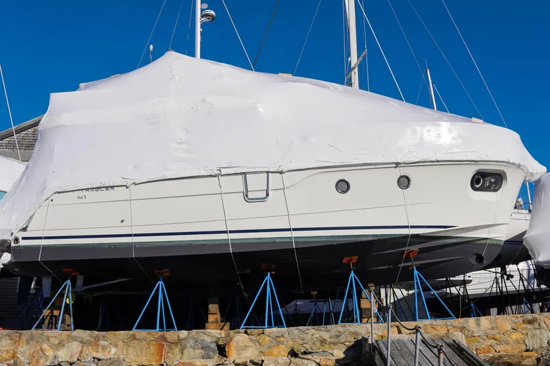 Slide: The Image of 2023 Beneteau Swift Trawler 41 Fly covered, elevated on stands, under clear blue sky. - 34