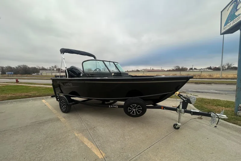 Slide: The Image of 2026 Lund 1700 Explorer Sport boat on trailer, parked outdoors under cloudy sky. - 1