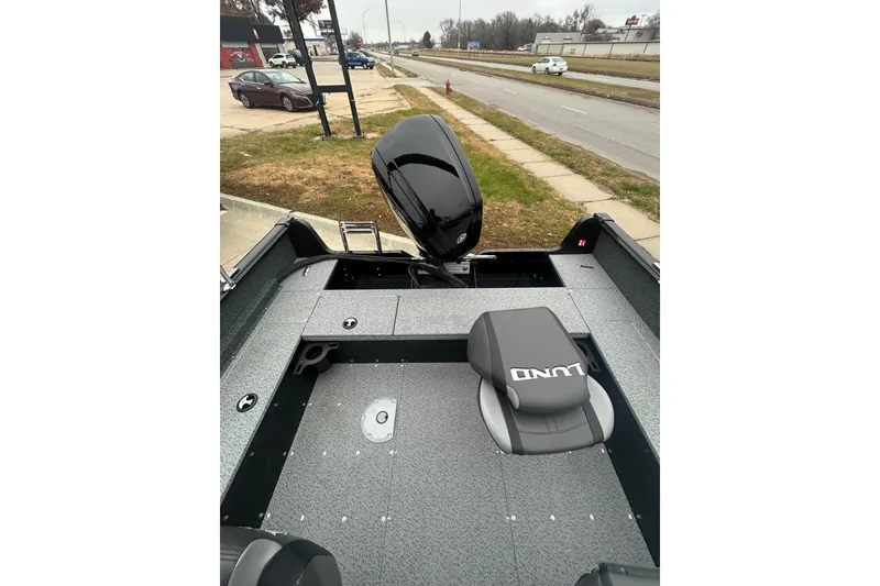 Slide: The Image of 2026 Lund 1700 Explorer Sport boat interior with seating and motor, parked roadside. - 27