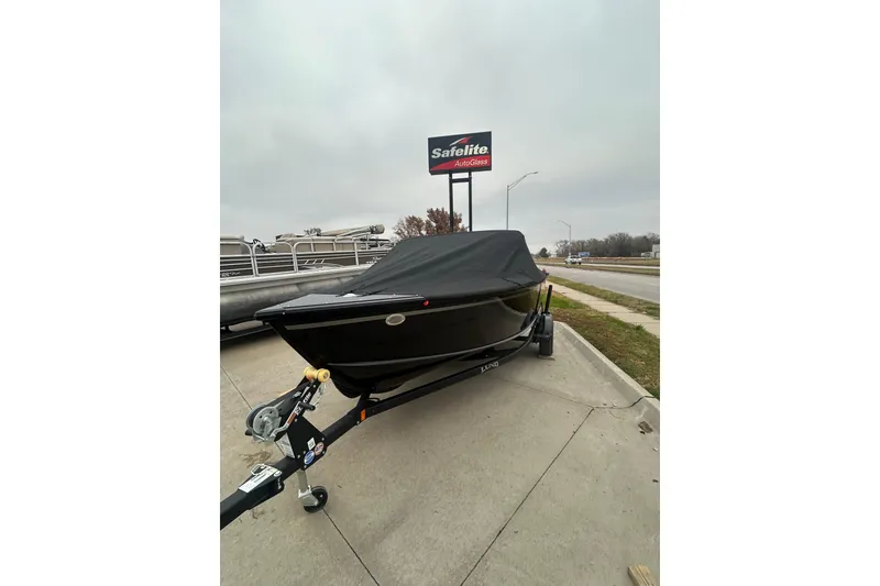 Slide: The Image of 2026 Lund 1700 Explorer Sport boat with cover on trailer, parked near Safelite AutoGlass sign. - 6