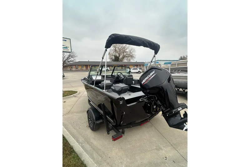 Slide: The Image of 2026 Lund 1700 Explorer Sport boat with Mercury outboard motor, parked on pavement. - 9