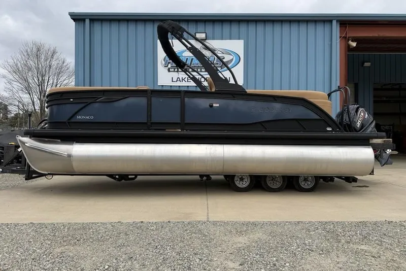 The Image of 2026 Godfrey Monaco 235 SFLC iMPACT pontoon boat parked outside a blue building. - 2
