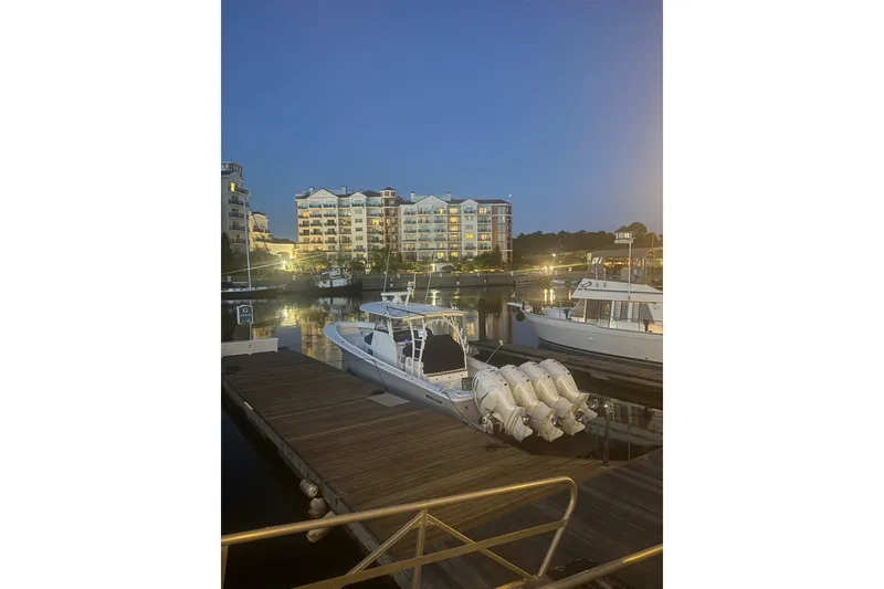 Slide: The Image of 2020 Regulator 41 boat docked at marina during evening, with illuminated buildings in background. - 70