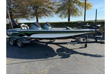 Slide: The Image of 2019 Nitro Z21 boat on trailer, parked outdoors with trees in the background. - 2