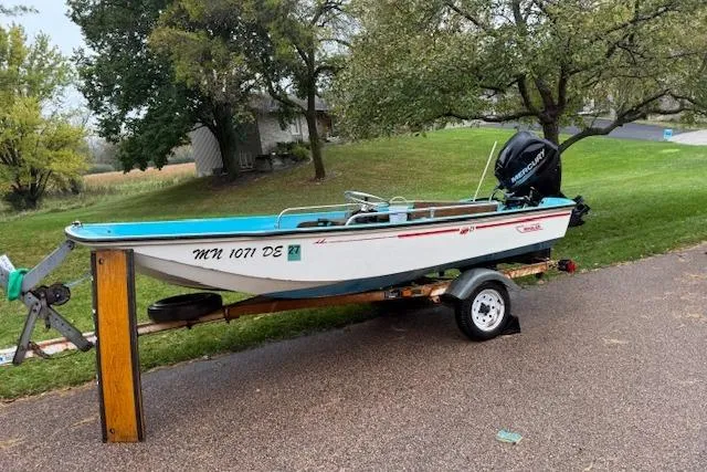 The Image of 1972 Boston Whaler Sourpuss 13 boat on trailer, parked on a driveway. - 1