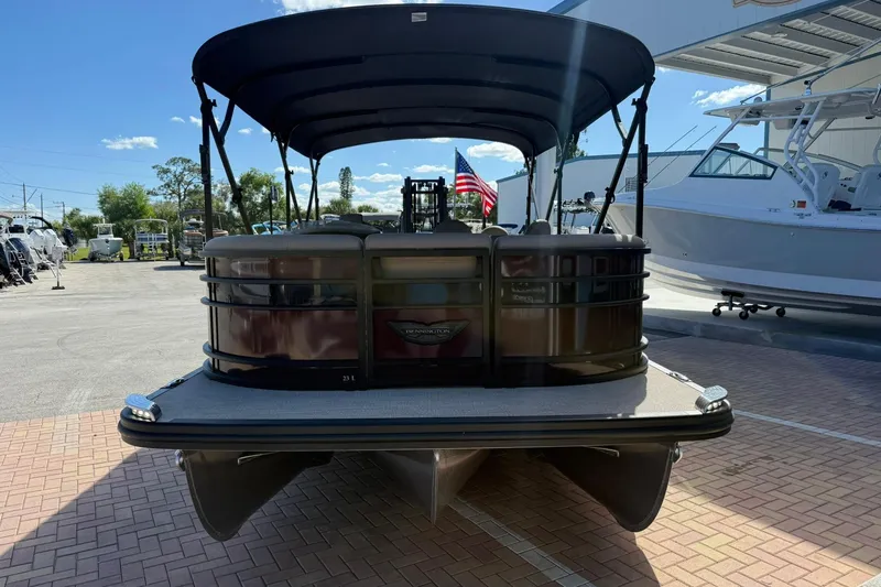 Slide: The Image of 2025 Bennington 23 LPD pontoon boat with canopy, parked on brick pavement. - 10