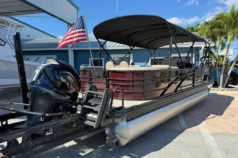 Slide: The Image of 2025 Bennington 23 LPD pontoon boat with Yamaha engine and American flag, docked outdoors. - 3