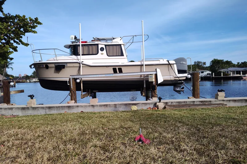 The Image of 2021 Ranger Tugs R-25 boat on lift by waterfront, clear sky background. - 0