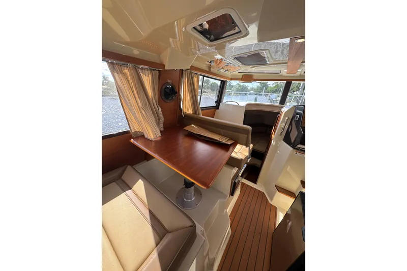 Slide: The Image of Interior of 2021 Ranger Tugs R-25, featuring a cozy dining area with wood accents. - 13