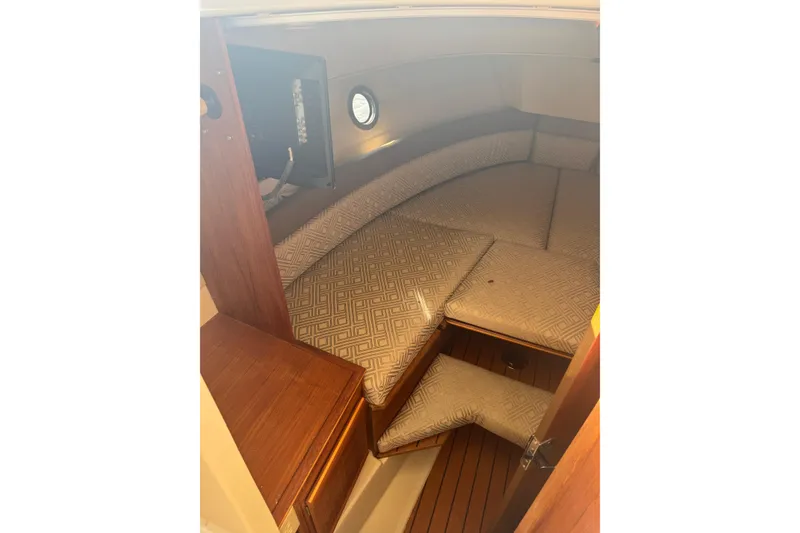 Slide: The Image of 2021 Ranger Tugs R-25 cabin interior with cushioned seating and wooden accents. - 16