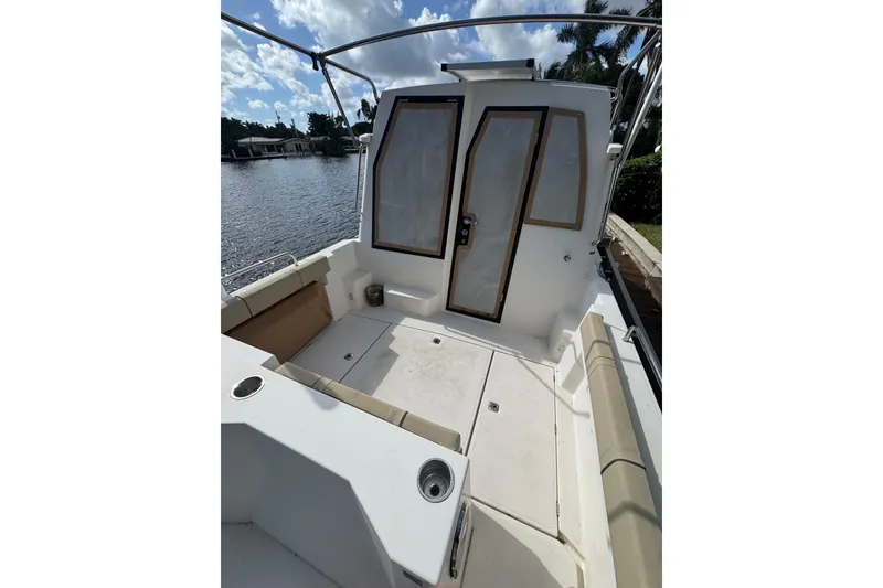 Slide: The Image of 2021 Ranger Tugs R-25 boat deck with seating, docked by a scenic waterfront. - 4