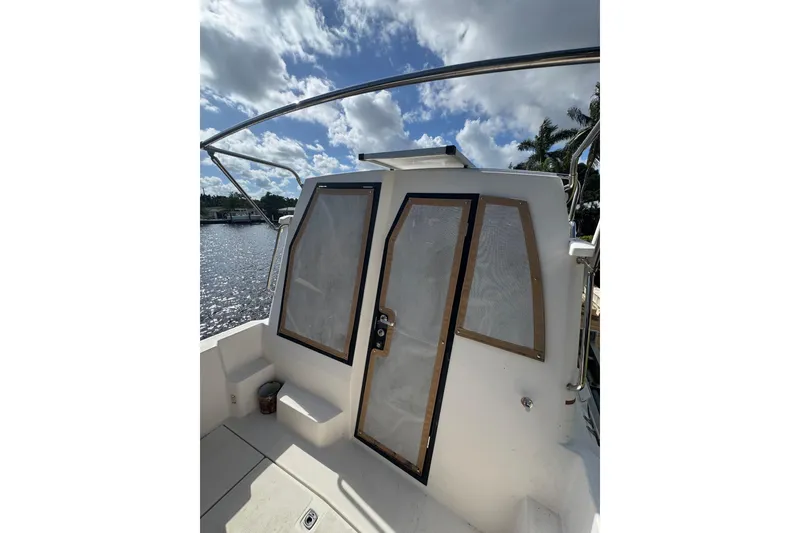 Slide: The Image of 2021 Ranger Tugs R-25 boat with cabin door, under a partly cloudy sky. - 6