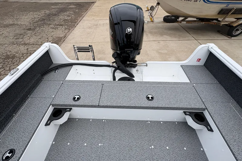 Slide: The Image of 2026 Lund 1800 Explorer Sport boat interior with motor, gray deck, and storage compartments. - 24