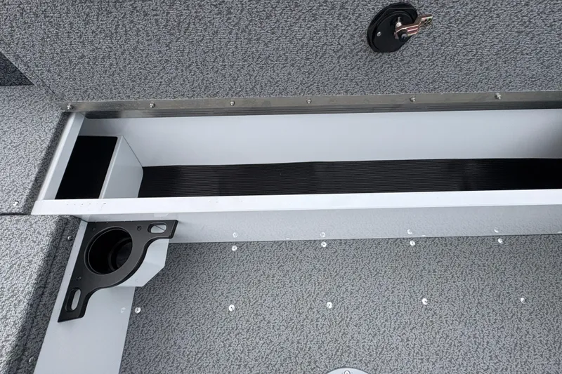 Slide: The Image of Interior storage compartment of 2026 Lund 1800 Explorer Sport boat, featuring cup holder and textured flooring. - 28
