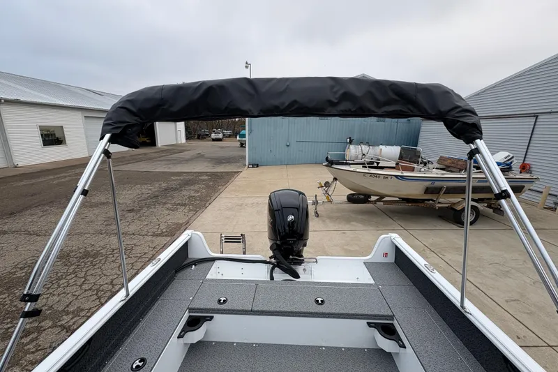 Slide: The Image of 2026 Lund 1800 Explorer Sport boat with bimini top and outboard motor in a marina. - 30