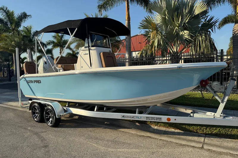 Slide: The Image of 2024 Sea Pro 202 Center Console boat on trailer, parked near palm trees. - 2