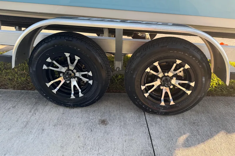 Slide: The Image of 2024 Sea Pro 202 Center Console boat on trailer, featuring Suzuki engine, parked outdoors. - 23