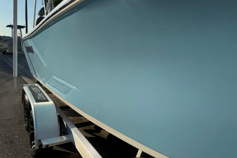 Slide: The Image of 2024 Sea Pro 202 Center Console boat on trailer, sunny day, palm trees in background. - 28