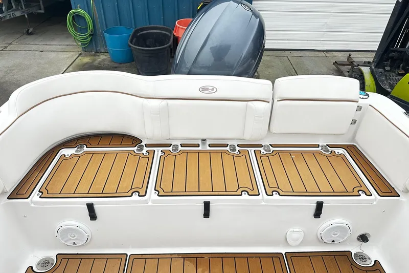 Slide: The Image of 2022 Sea Hunt Ultra 234 boat deck with teak flooring and white seating. - 12