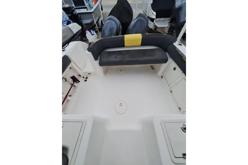 Slide: The Image of Interior of a 2006 Century 2400 Walkaround boat, featuring seating and compact kitchen area. - 13