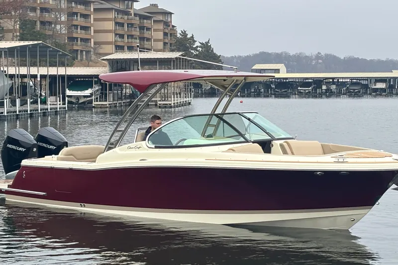 Slide: The Image of 2026 Chris-Craft Calypso 28 boat with red canopy on a calm lake near docks. - 3