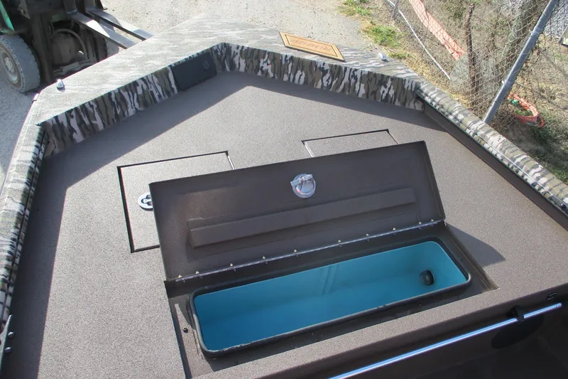 Slide: The Image of Avid 18 Rogue CC 2026 boat with open storage compartment, camo trim, and blue interior. - 11