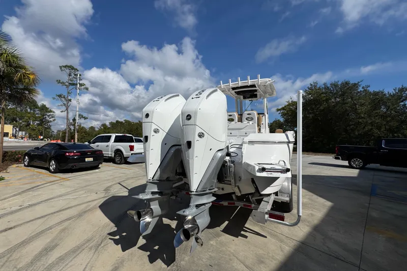Slide: The Image of 2026 Caymas 291 boat with dual outboard motors in a parking lot under a blue sky. - 14