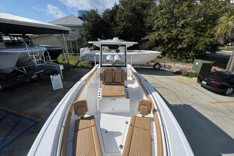 Slide: The Image of 2026 Caymas 291 boat with tan seating, displayed outdoors near other boats and vehicles. - 23