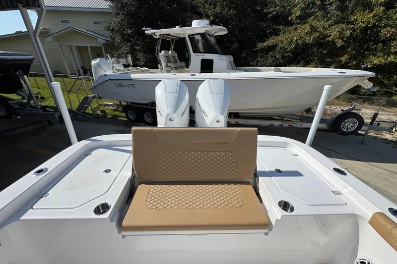 Slide: The Image of 2026 Caymas 291 boat with tan seating, docked near a Solace boat on a trailer. - 42