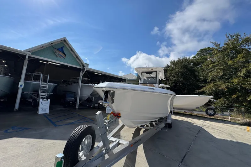 Slide: The Image of 2026 Caymas 291 boat on trailer outside a marina under a clear blue sky. - 6