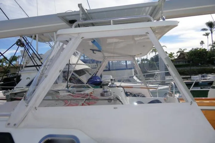 Slide: The Image of 2008 Catalina 400 MK II sailboat cockpit with clear enclosure and marina background. - 55