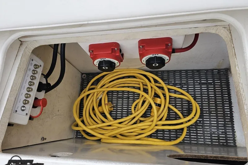 Slide: The Image of Storage compartment with yellow cable and electrical switches in a 2004 Black Thunder 460 boat. - 107