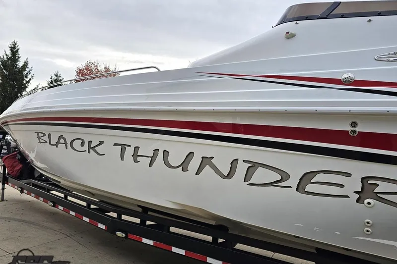 Slide: The Image of 2004 Black Thunder 460 boat on trailer, featuring sleek white and red design. - 20