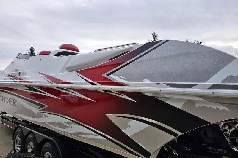 Slide: The Image of 2004 Black Thunder 460 boat with sleek red, white, and gray design on a trailer. - 25