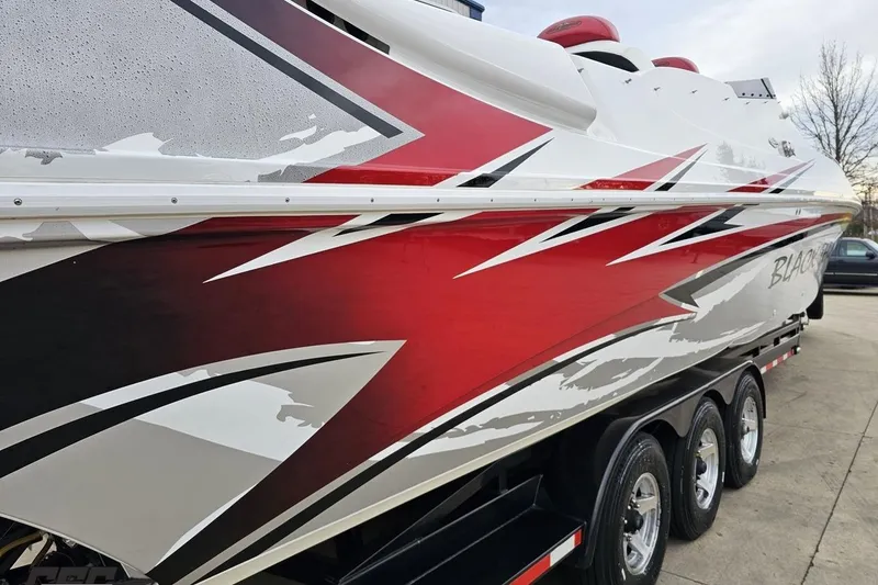 Slide: The Image of 2004 Black Thunder 460 boat with striking red and white graphics on a trailer. - 33