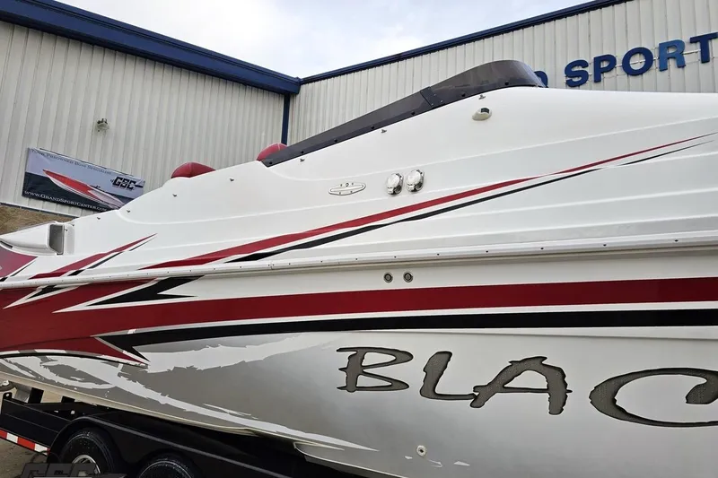 Slide: The Image of 2004 Black Thunder 460 boat with red and black accents, parked outside a building. - 5