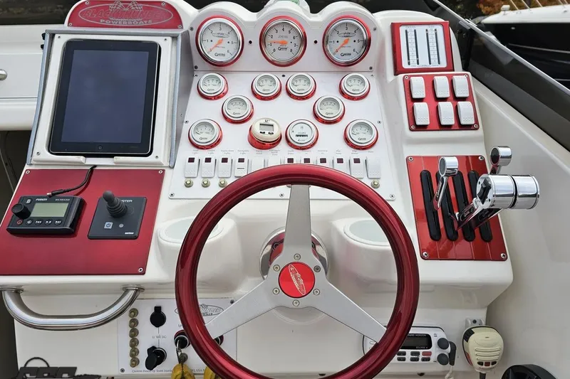 Slide: The Image of Control panel of a 2004 Black Thunder 460 powerboat with gauges and steering wheel. - 56