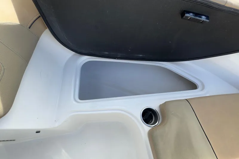 Slide: The Image of 2022 Bayliner VR6 Bowrider OB storage compartment with cup holder and beige seating. - 48
