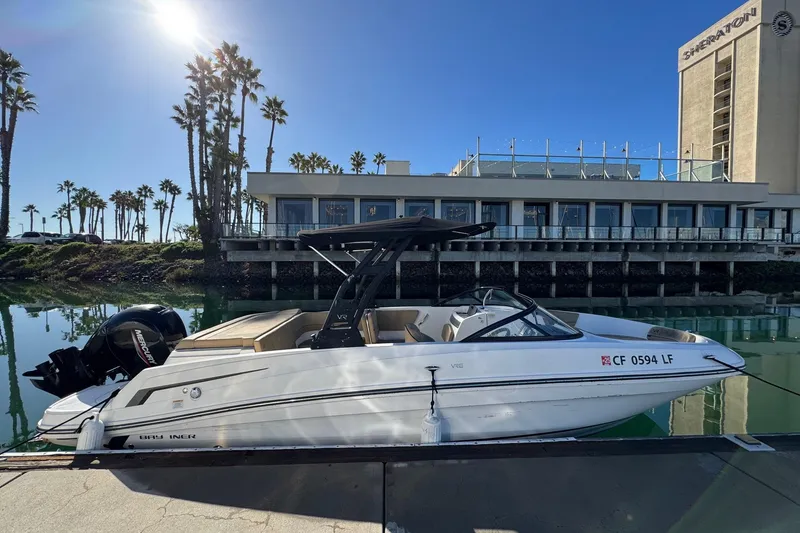 Slide: The Image of 2022 Bayliner VR6 Bowrider OB docked near a waterfront hotel with palm trees. - 8