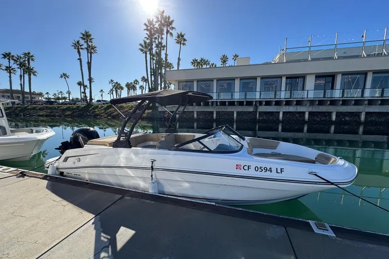Slide: The Image of 2022 Bayliner VR6 Bowrider OB docked by waterfront with palm trees and building. - 9