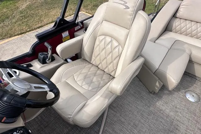 Slide: The Image of Captain's seat of 2015 Bennington 2350 QCL boat with beige upholstery and steering wheel. - 14