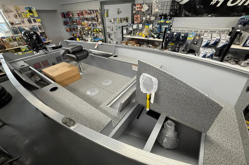 Slide: The Image of 2026 Lund Fury 1600 Tiller boat interior in a showroom with fishing accessories. - 3