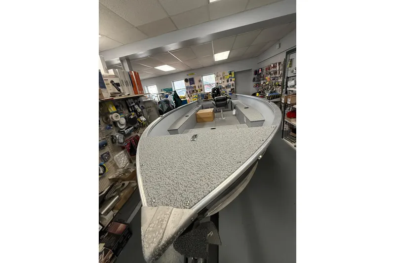 Slide: The Image of 2026 Lund Fury 1600 Tiller boat displayed in a showroom with various accessories. - 4